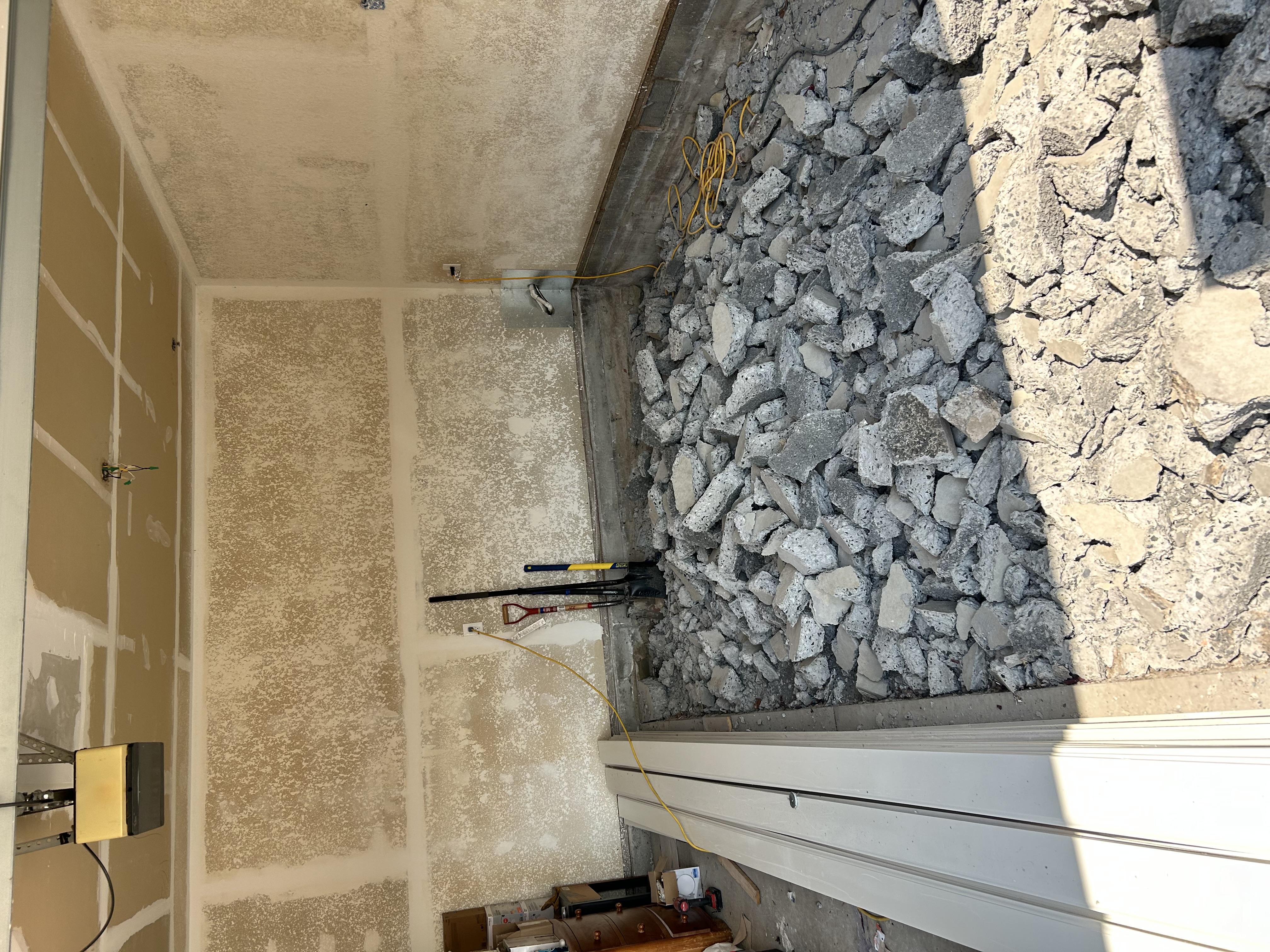 Garage demo – wide view of broken concrete chunks with tools and door