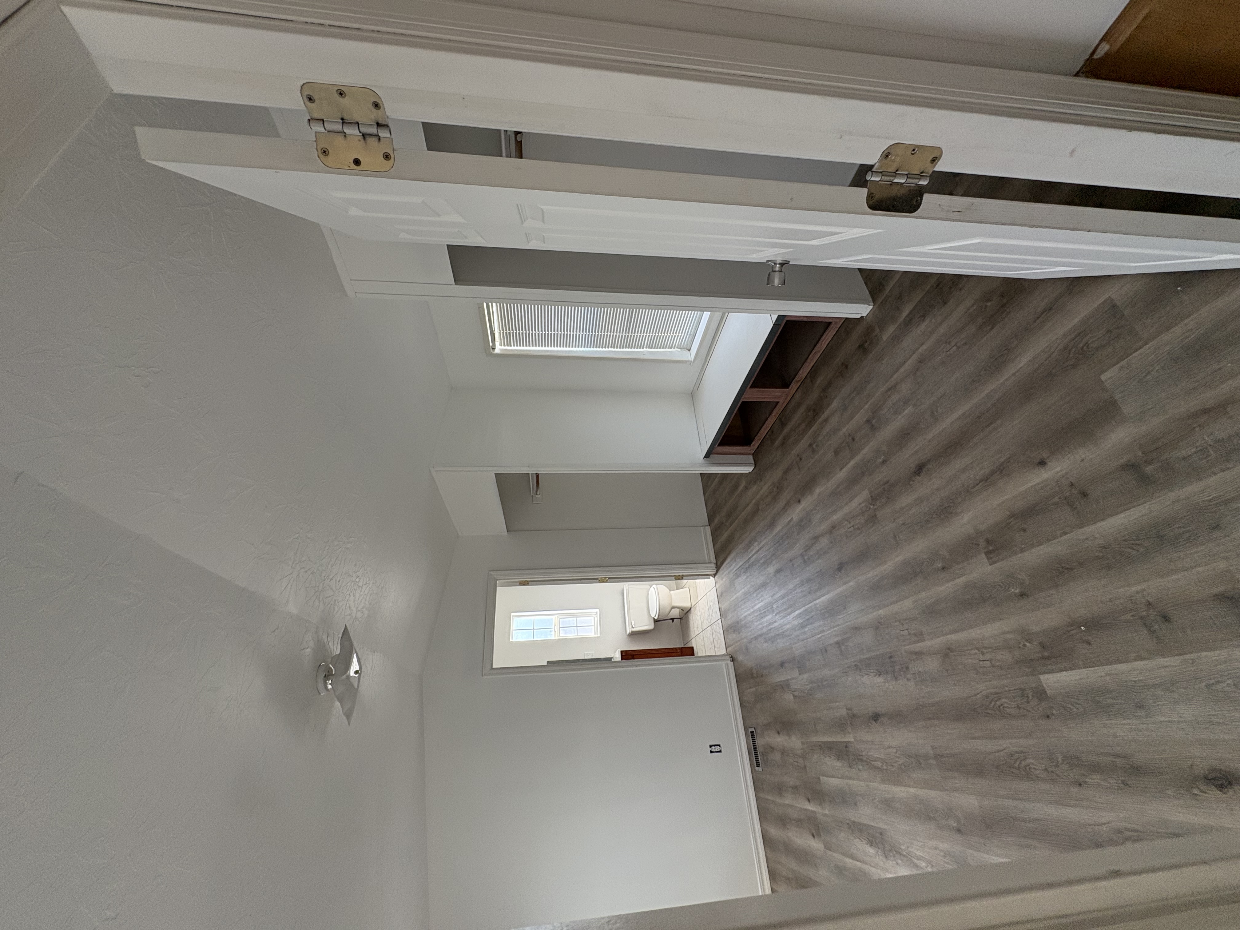 Finished hallway with built-in bench, closets, and bathroom view