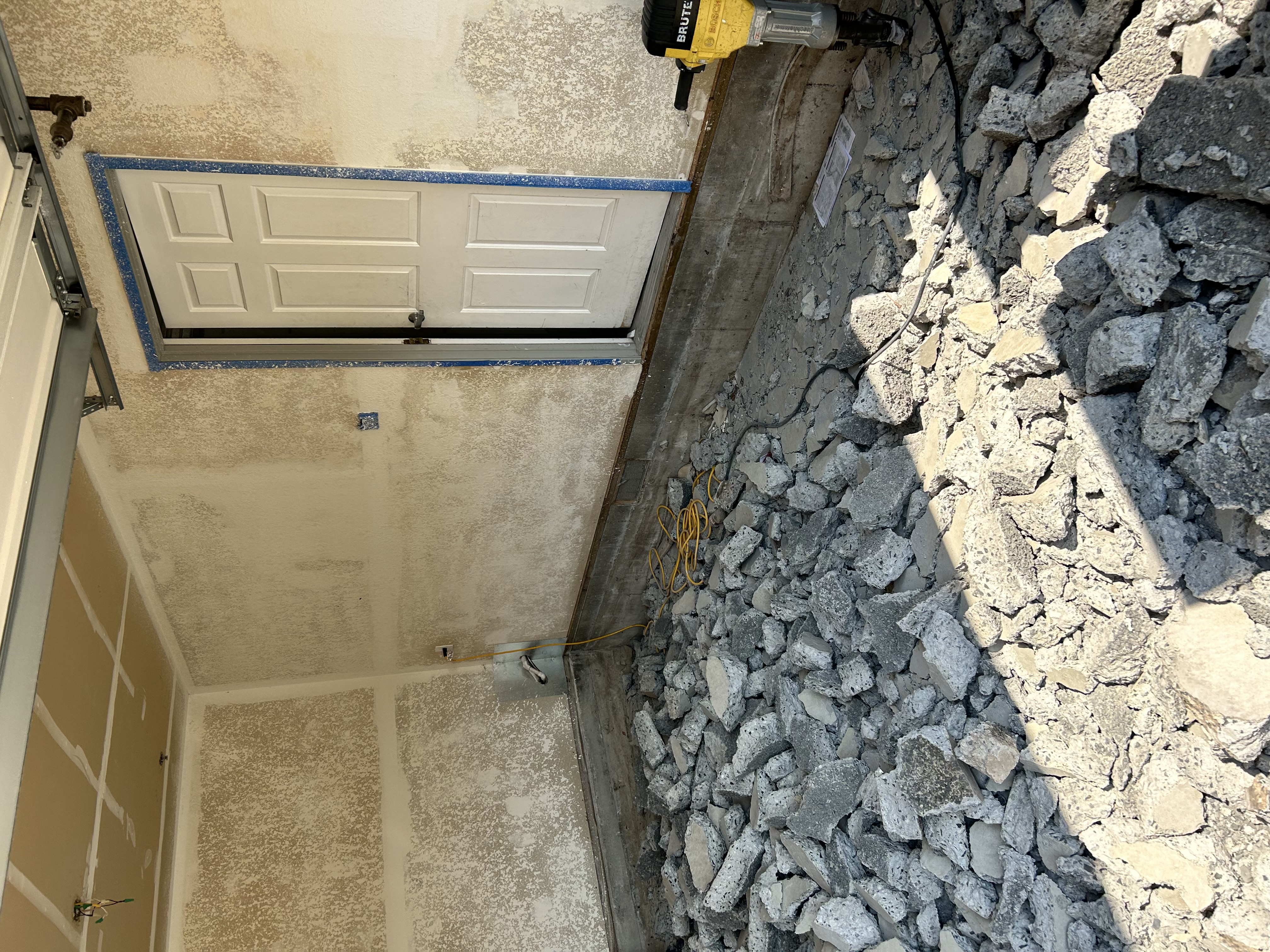 Garage concrete demo – broken slab chunks with Brute jackhammer and door visible