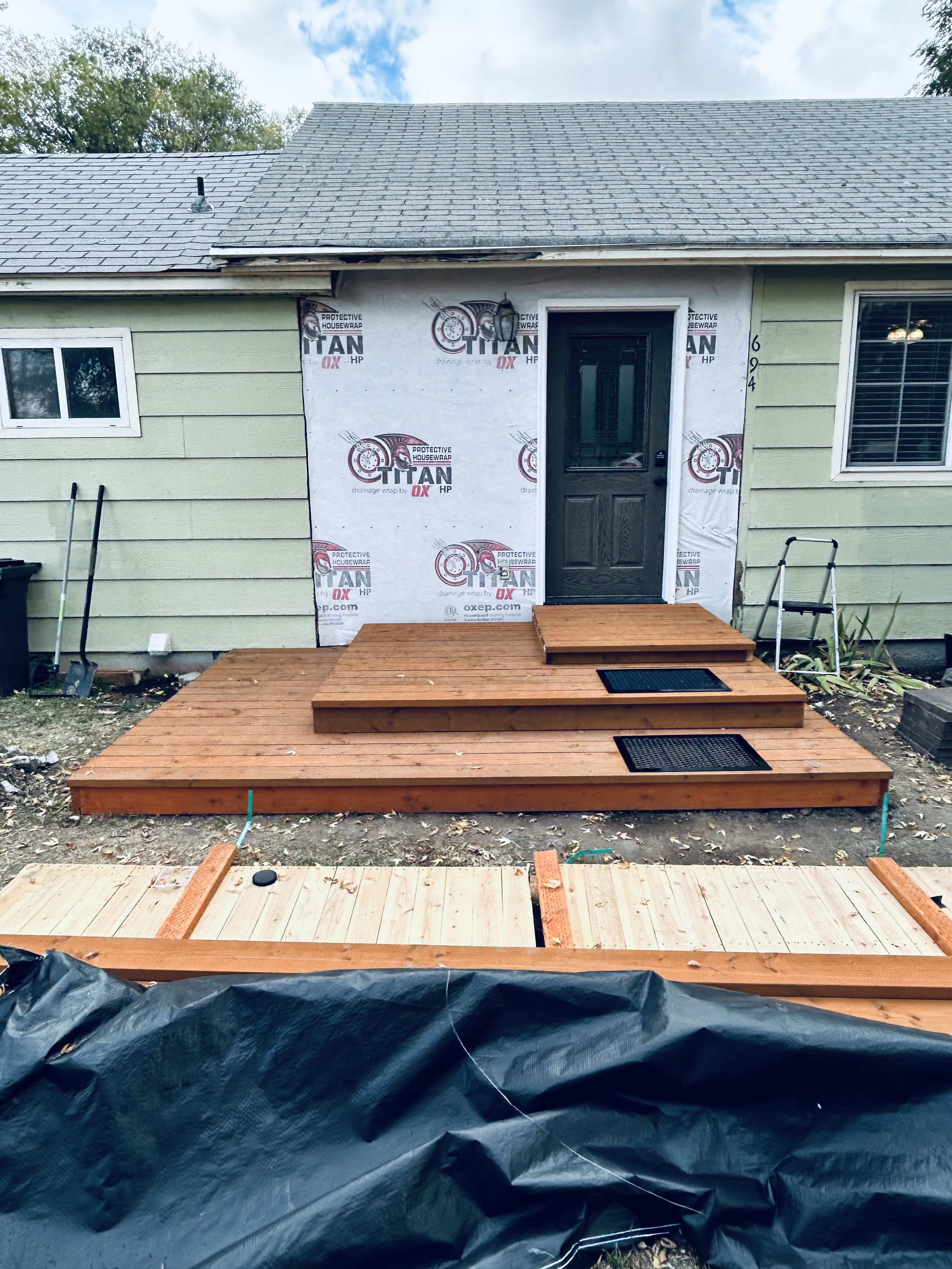 Cedar front deck stained – housewrap mid-siding install