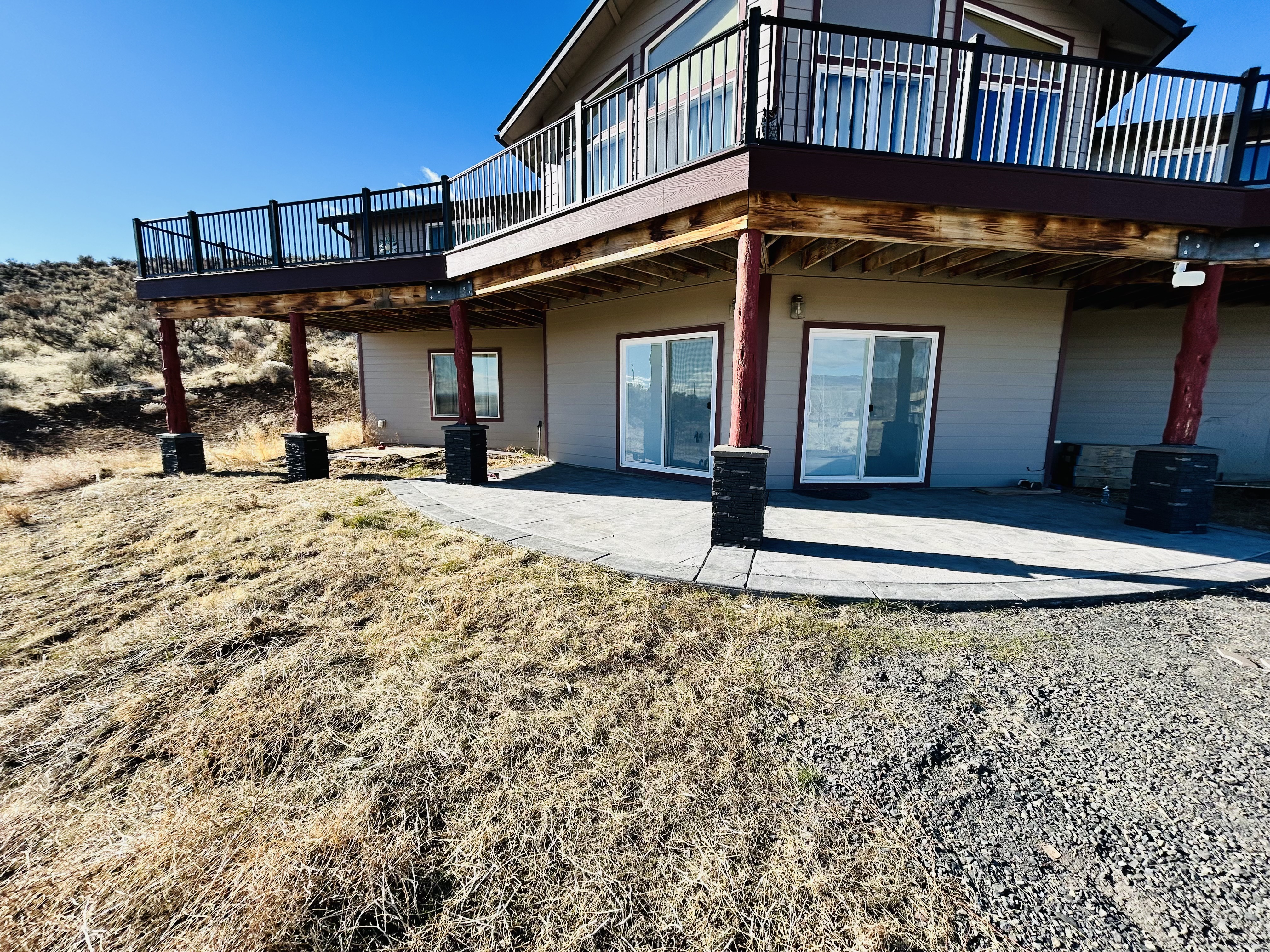 Stamped concrete patio with stone column bases and red log posts