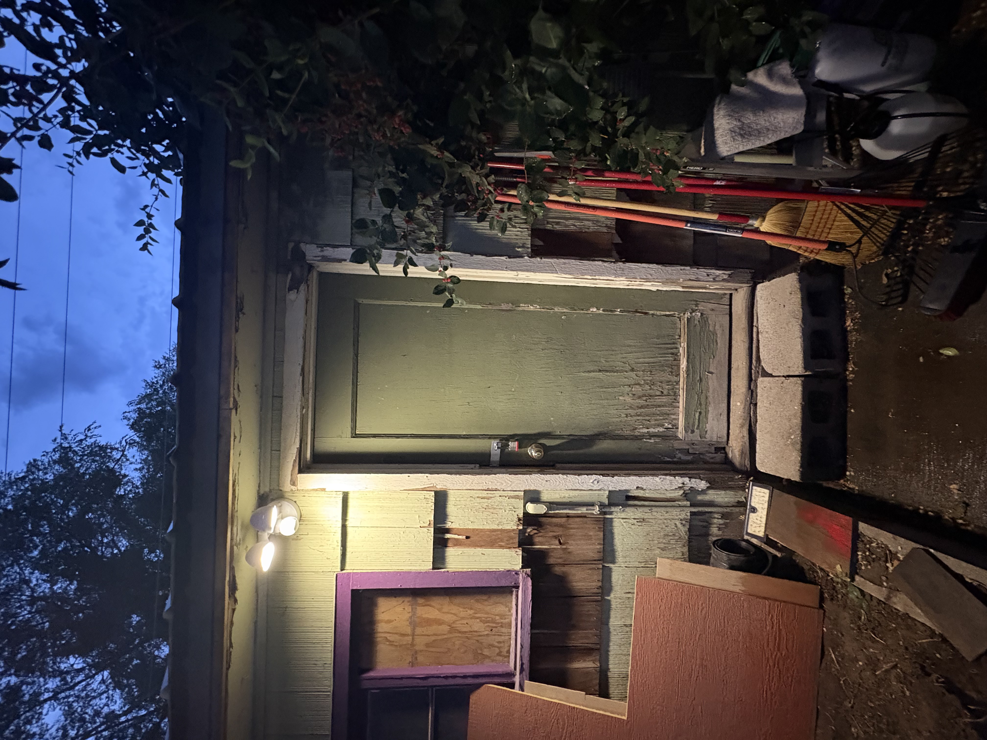 Exterior before – peeling siding and old door at night